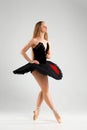 Girl in a black ballet dress. Ballerina in a dark ballet tutu on a light background. The young ballerina is warming up