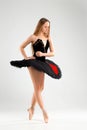 Girl in a black ballet dress. Ballerina in a dark ballet tutu on a light background. The young ballerina is warming up