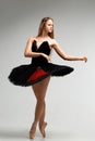 Girl in a black ballet dress. Ballerina in a dark ballet tutu on a light background. The young ballerina is warming up