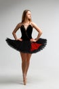 Girl in a black ballet dress. Ballerina in a dark ballet tutu on a light background. The young ballerina is warming up