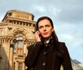 Girl in black coat with mobile phone in the City