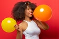 Girl with black curly hair inflates two balloons