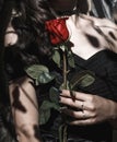 A girl in a black dress with a red rose. Gothic style, female hand with black nails, symbol of love and death Royalty Free Stock Photo