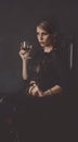 A girl in a black dress is sitting on a chair with a glass of wine Royalty Free Stock Photo