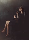 A girl in a black dress is sitting on a chair with a glass of wine Royalty Free Stock Photo
