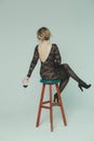 A girl in a black guipure dress sits with her back on a bar stool holding a glass of wine in her hand Royalty Free Stock Photo