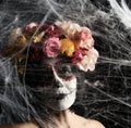 Girl with black hair is dressed in a wreath of multi-colored roses and makeup is made on her face Sugar skull to the day of the Royalty Free Stock Photo