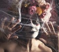 Girl with black hair is dressed in a wreath of multi-colored roses and makeup is made on her face Sugar skull to the day of the Royalty Free Stock Photo