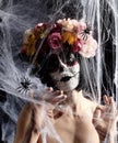 Girl with black hair is dressed in a wreath of multi-colored roses and makeup is made on her face Sugar skull to the day of the Royalty Free Stock Photo