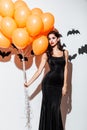 Girl in black halloween costume with eyes closed holding balloons Royalty Free Stock Photo