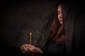 The girl in black holds a burning church candle in her hands. Mourning, grief