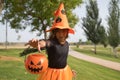 Girl in black shirt, witch hat and orange skirt with pumpkin on arm and hand trying to grab camera celebrating halloween. Autumn Royalty Free Stock Photo