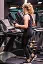 A girl in a black sports uniform runs on a treadmill in a sports hall Royalty Free Stock Photo