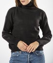 a girl in a black wool sweater and blue jeans on a white background