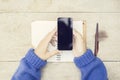 Girl with blank black cell phone and opened diary on wooden table Royalty Free Stock Photo