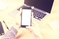 Girl with blank smartphone and opened laptop on wooden table, mo Royalty Free Stock Photo