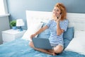 Girl blogger talking on mobile phone sitting on bed. Happy woman having phone conversation Royalty Free Stock Photo