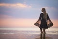 A girl with blond chic hair in a black bikini and a lace shawl walks along the estuary Royalty Free Stock Photo