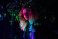 Girl in blond curly hair, illuminated by multi-colored light.