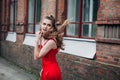 Girl with blond flowing long hair and beautiful make-up, in a long red dress, is walking along the street Royalty Free Stock Photo