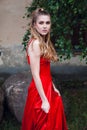 Girl with blond flowing long hair and beautiful make-up, in a long red dress, stands on the street Royalty Free Stock Photo