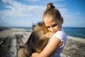 Girl with blond hair with smile hugs pomeranian dog with golden hair on seashore near Black Sea Royalty Free Stock Photo