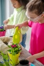 Girl with blond hair watering a violet.