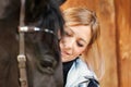 Girl blonde in blue quilted vest with ponytail plays with her horse, portraits of the woman with focus on her head close-up. Royalty Free Stock Photo