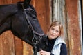 Girl blonde in blue quilted vest with ponytail plays with her horse, portraits of the woman with focus on her head close-up. Royalty Free Stock Photo