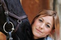 Girl blonde in blue quilted vest with ponytail plays with her horse, portraits of the woman with focus on her head close-up. Royalty Free Stock Photo