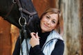 Girl blonde in blue quilted vest with ponytail plays with her horse, portraits of the woman with focus on her head close-up. Royalty Free Stock Photo