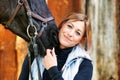 Girl blonde in blue quilted vest with ponytail plays with her horse, portraits of the woman with focus on her head close-up. Royalty Free Stock Photo