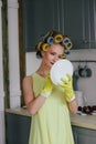 The girl the blonde in curlers and in a yellow dress cleans up with gloves and a sponge. Royalty Free Stock Photo