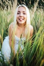 Girl blonde sitting in grass shows tongue fun