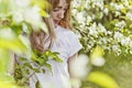 Girl in blossoming Apple tree. spring flowering Apple tree. A beautiful young woman in a white t-shirt looks down. Royalty Free Stock Photo