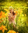 A girl in a blouse and a knitted hat sits among orange yellow Lilium flowers Royalty Free Stock Photo