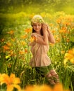 A girl in a blouse and a knitted hat sits among orange yellow lily flowers Royalty Free Stock Photo