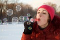 Girl blow bubbles in winter park.