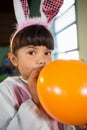 Girl blowing balloon during birthday party at home