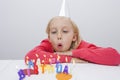 Girl blowing birthday candles at table in house Royalty Free Stock Photo