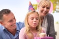 Girl, blowing or candle at happy birthday, party or cake as fun wish, family or bonding together. Papa, mama or child or