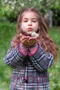 Girl blowing on a dandelion in a spring park. Happy child has fun outdoors. Royalty Free Stock Photo