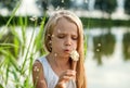 Girl blowing on dandelion, summer in nature