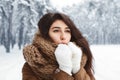 Girl Blowing On Hands In Gloves Standing In Snowy Forest