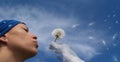 Girl blowing seeds out of a dandelion Royalty Free Stock Photo