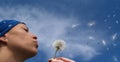 Girl blowing seeds out of a dandelion Royalty Free Stock Photo