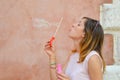 Girl blowing soap bubbles against colourful backdrop Royalty Free Stock Photo