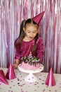 Girl blows out burning candle on cake making cherished wish on sixth birthday Royalty Free Stock Photo