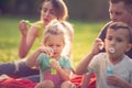 Girl blows soap bubbles with her family in the park Royalty Free Stock Photo