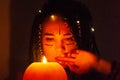 Girl with blue dreadlocks conjures at night in a dark room, candle fire and a cow skull. Royalty Free Stock Photo
